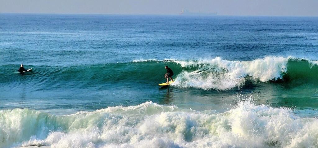 Une plage avec des vagues et un surfeur.