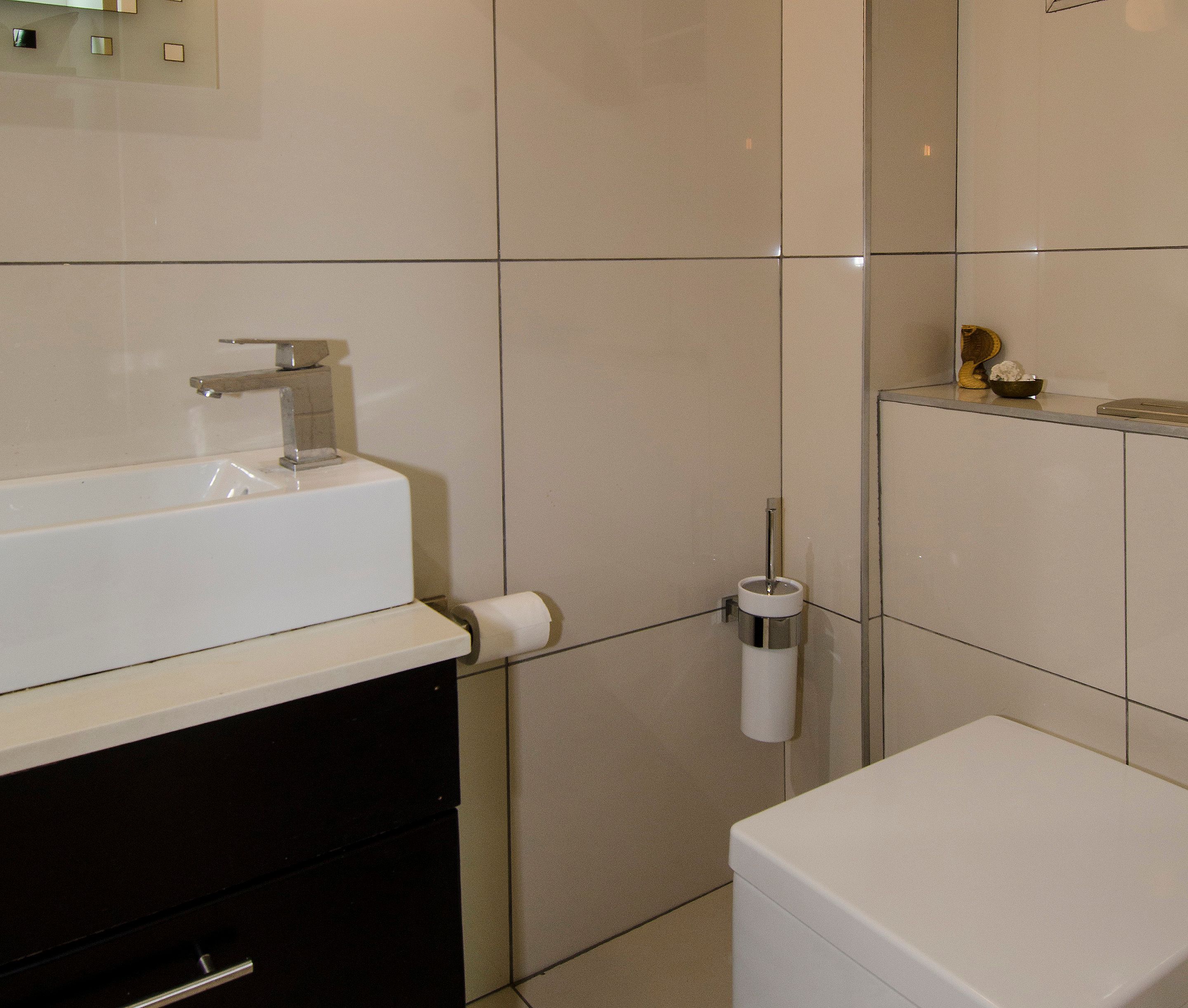 Une salle de bain avec un lavabo blanc, des toilettes et un distributeur de serviettes.