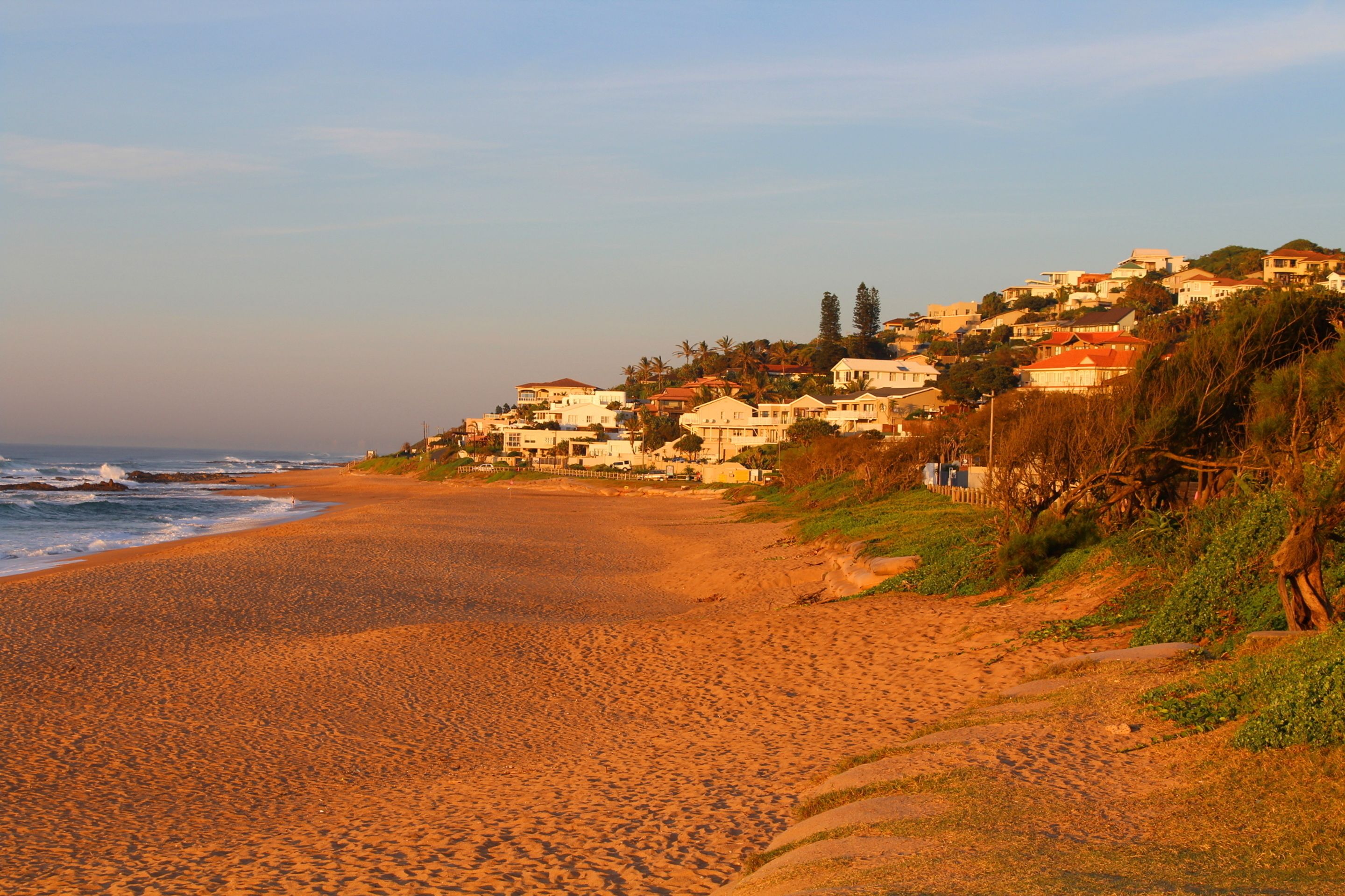 A beach with houses on a hillside.