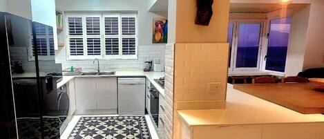 A compact kitchen with a window, a tiled floor, and a dining area with a view.