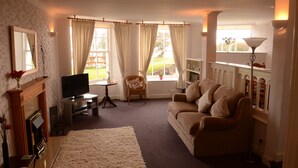 A living room with a fireplace, sofa, television, and a view of the outdoors.