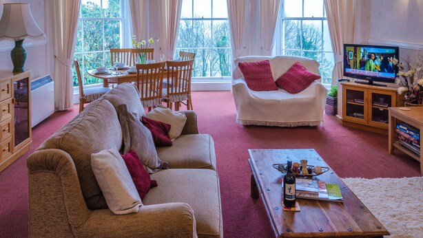 A cozy living room with a sofa, armchair, coffee table, and a TV.