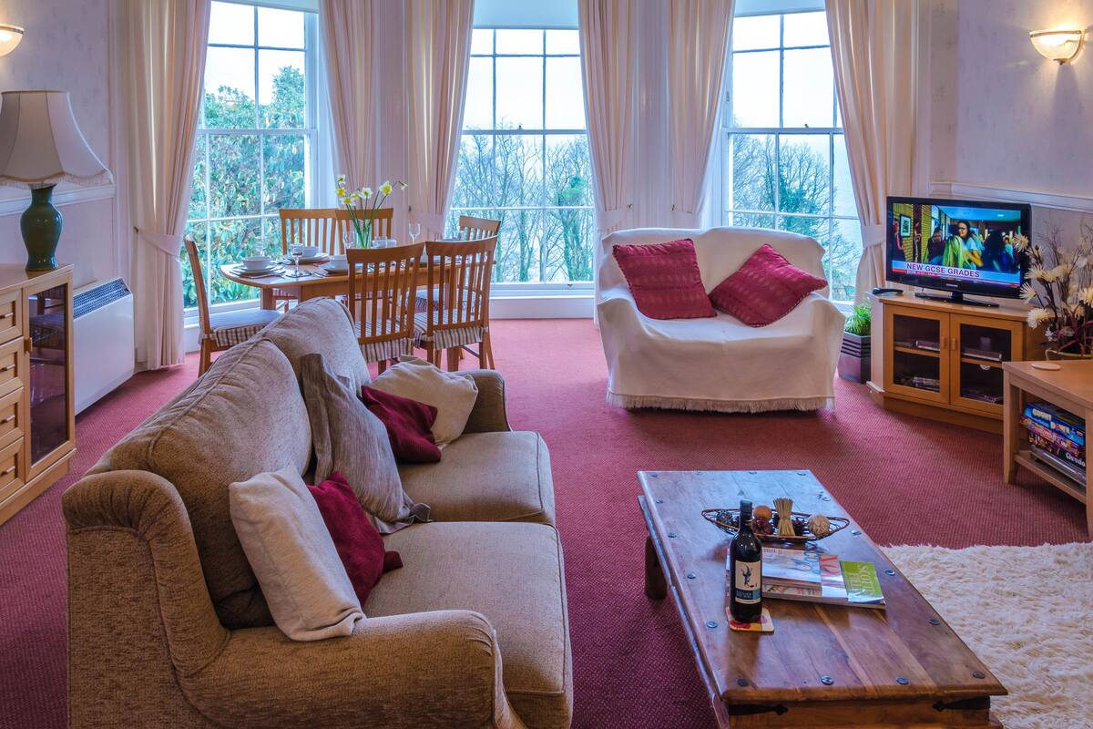 A cozy living room with a sofa, armchair, coffee table, and a TV.