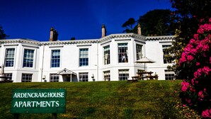 A large, white, multi-story building with a sign reading "ArdenCraig House Apartments".