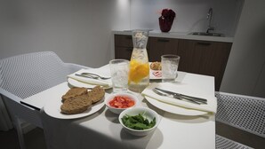 Una mesa de comedor con mantel blanco, platos, cuencos y cubiertos.