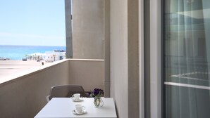 Un balcón con una mesa, dos tazas y un jarrón con flores.