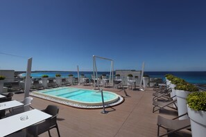 A rooftop pool area with lounge chairs and tables, overlooking the sea. - M&F Hotel (Gallipoli)