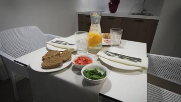 A dining table with a white tablecloth, plates, bowls, and cutlery.