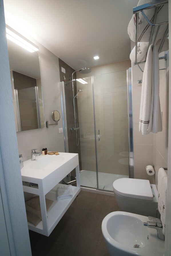 A modern bathroom with a glass-enclosed shower, a white sink, and a toilet.