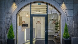 A modern hotel entrance with a stone facade, a reception desk, and two potted plants. - 296 Heritage Apartments (Vila Nova de Gaia)