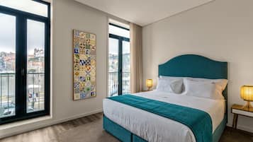 Habitación de hotel con una cama grande, vista a la ciudad y una obra de arte colorida en la pared.
