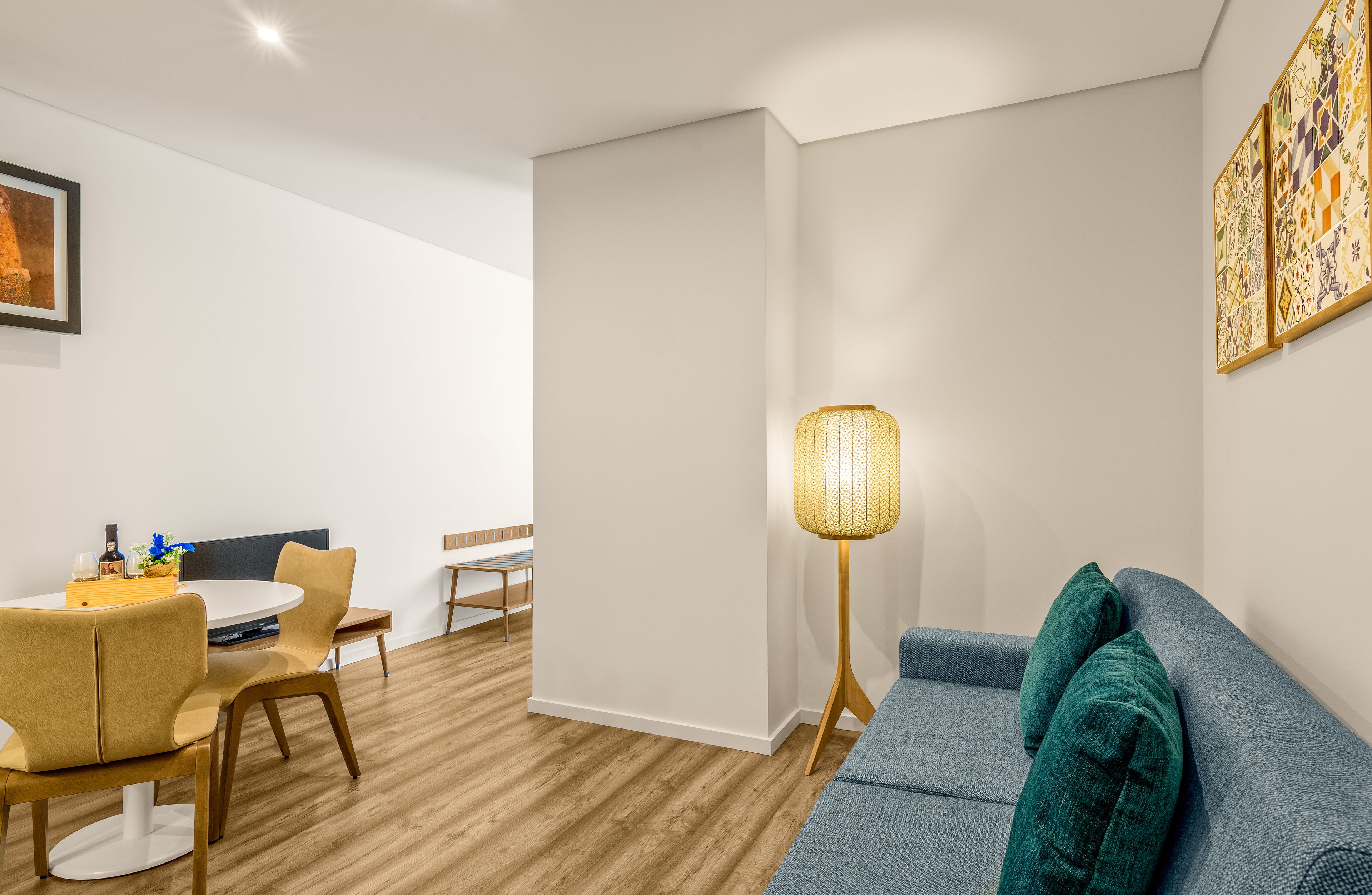 A modern living room with a sofa, a dining area with chairs and a table, and a floor lamp.