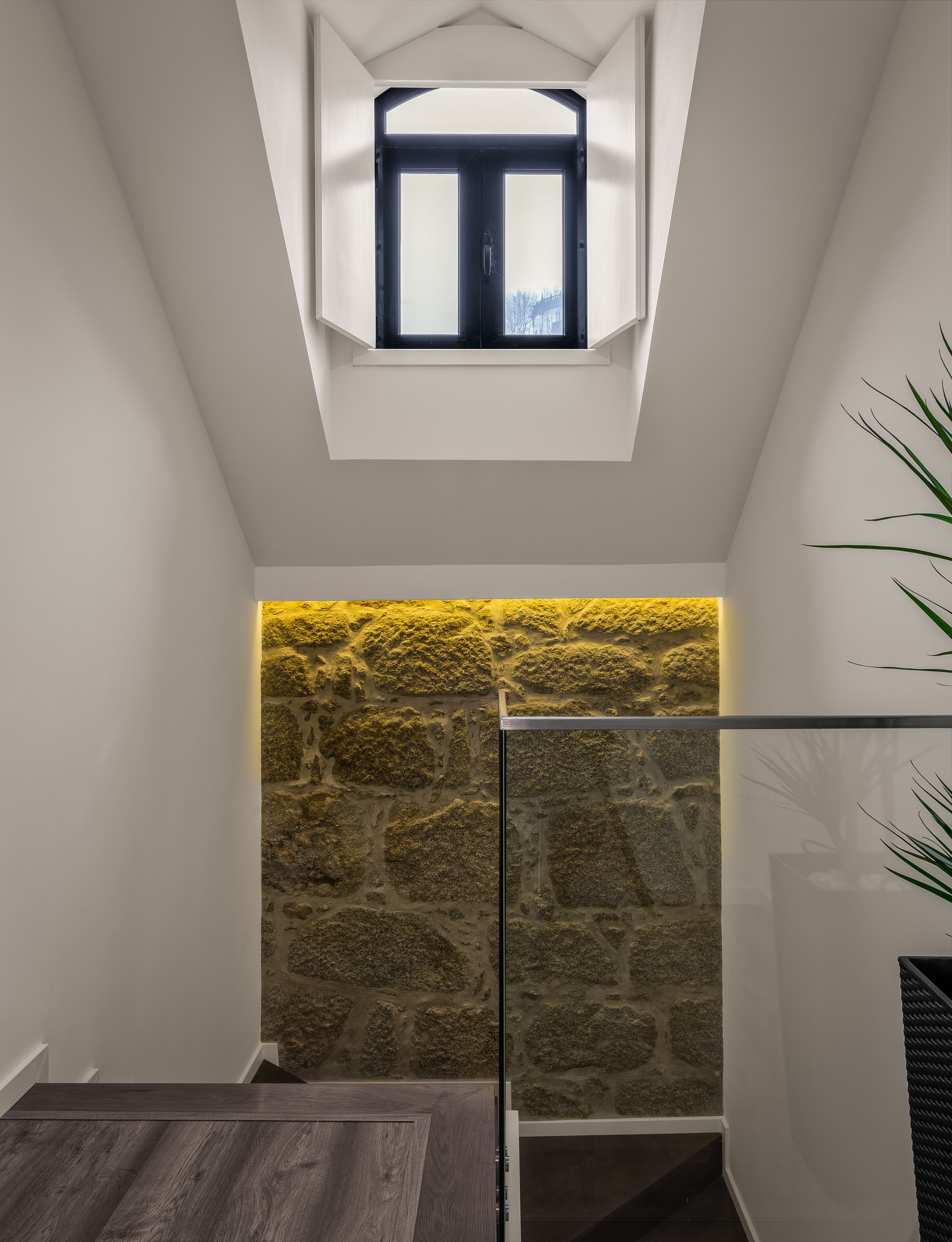 Un intérieur moderne avec un mur en pierre, une porte en verre et une petite fenêtre.