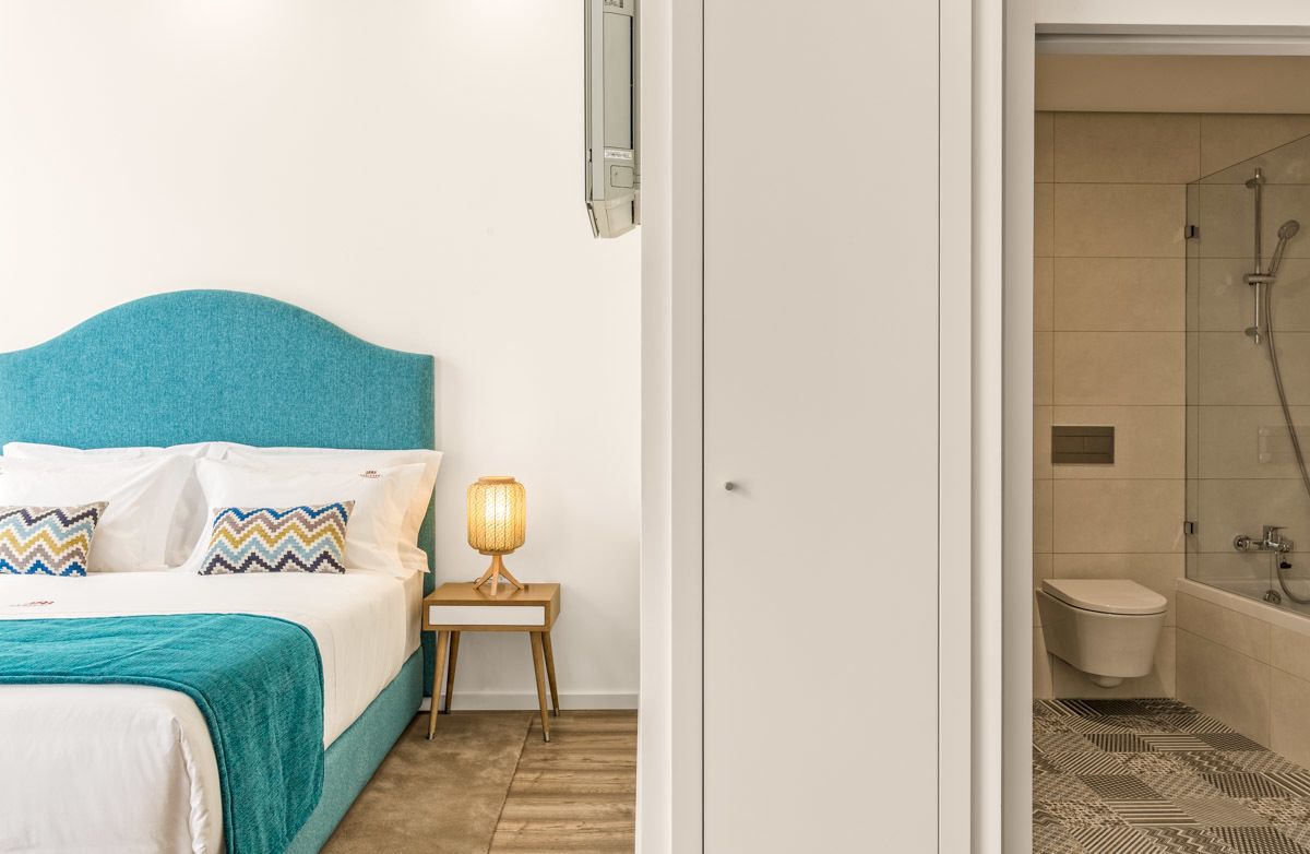 A bedroom with a teal headboard, a bedside lamp, and a patterned rug.