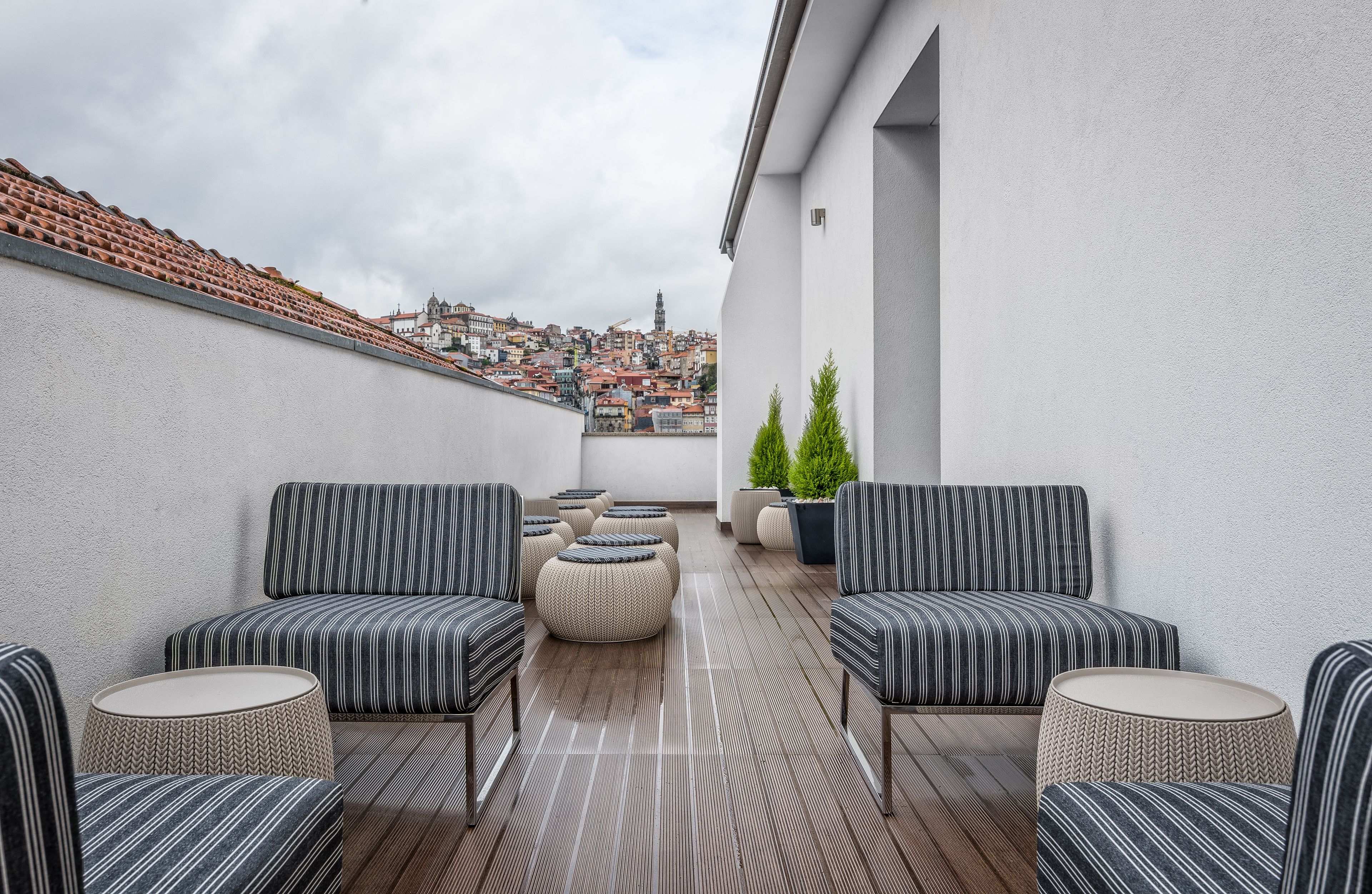 Une terrasse sur le toit, agrémentée de canapés à rayures, de poufs ronds et de plantes en pot.