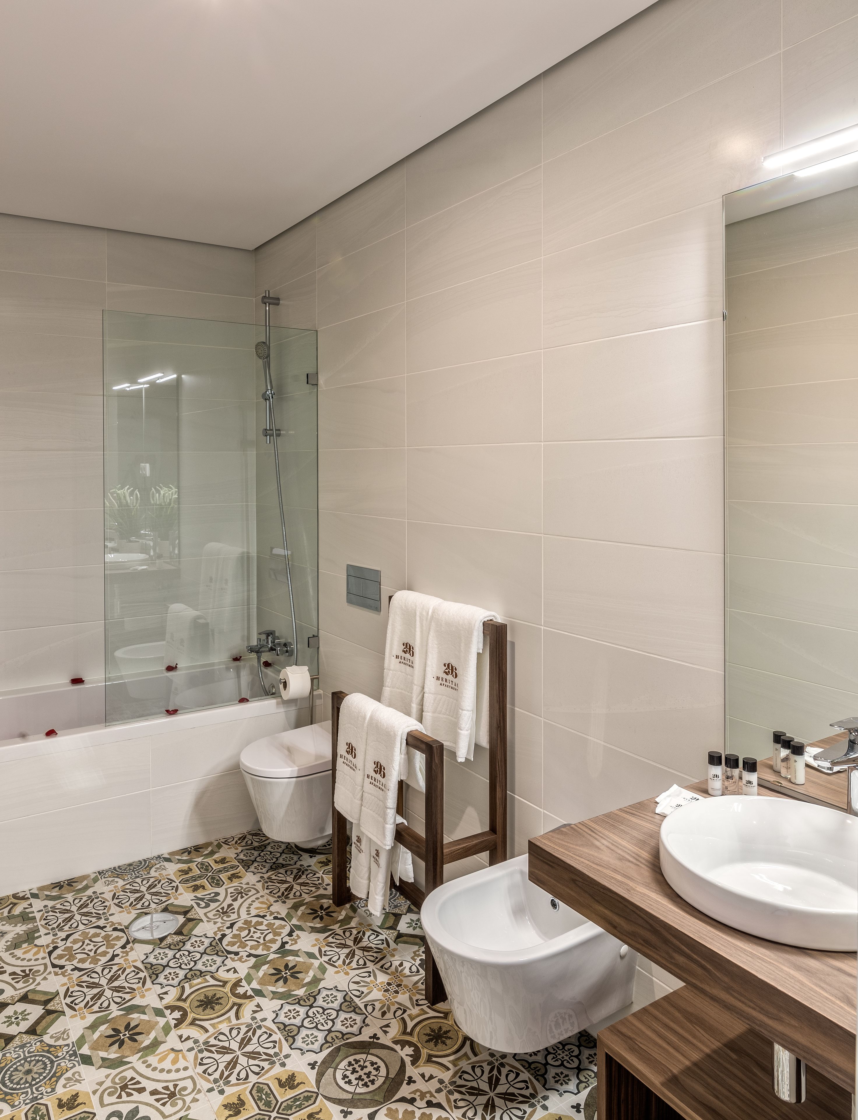 A modern bathroom with a glass-enclosed shower, a toilet, a sink, and a mirror.