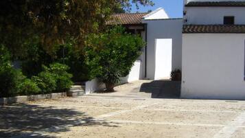 A courtyard with a white building, a tiled roof, and potted plants.