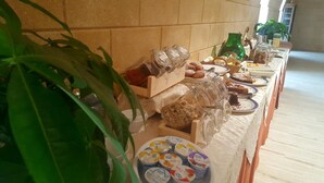 Een buffettafel met diverse gerechten en toevoegingen, waaronder potjes yoghurt en een groene fles.