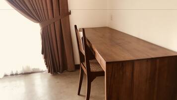 Una mesa de madera con sillas, una cortina y una pared sencilla.