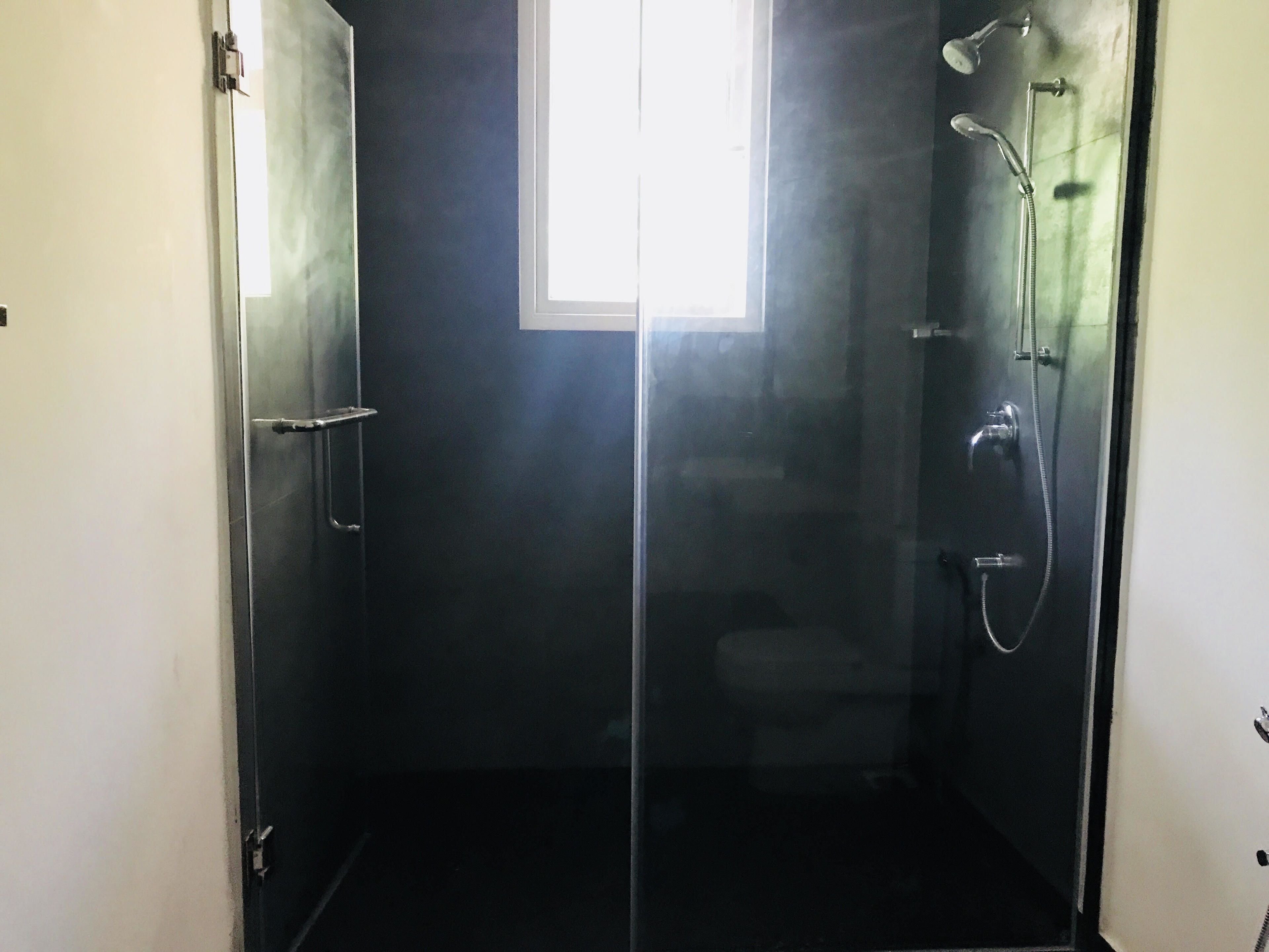 A glass-enclosed shower stall with a window, a door, and a showerhead.