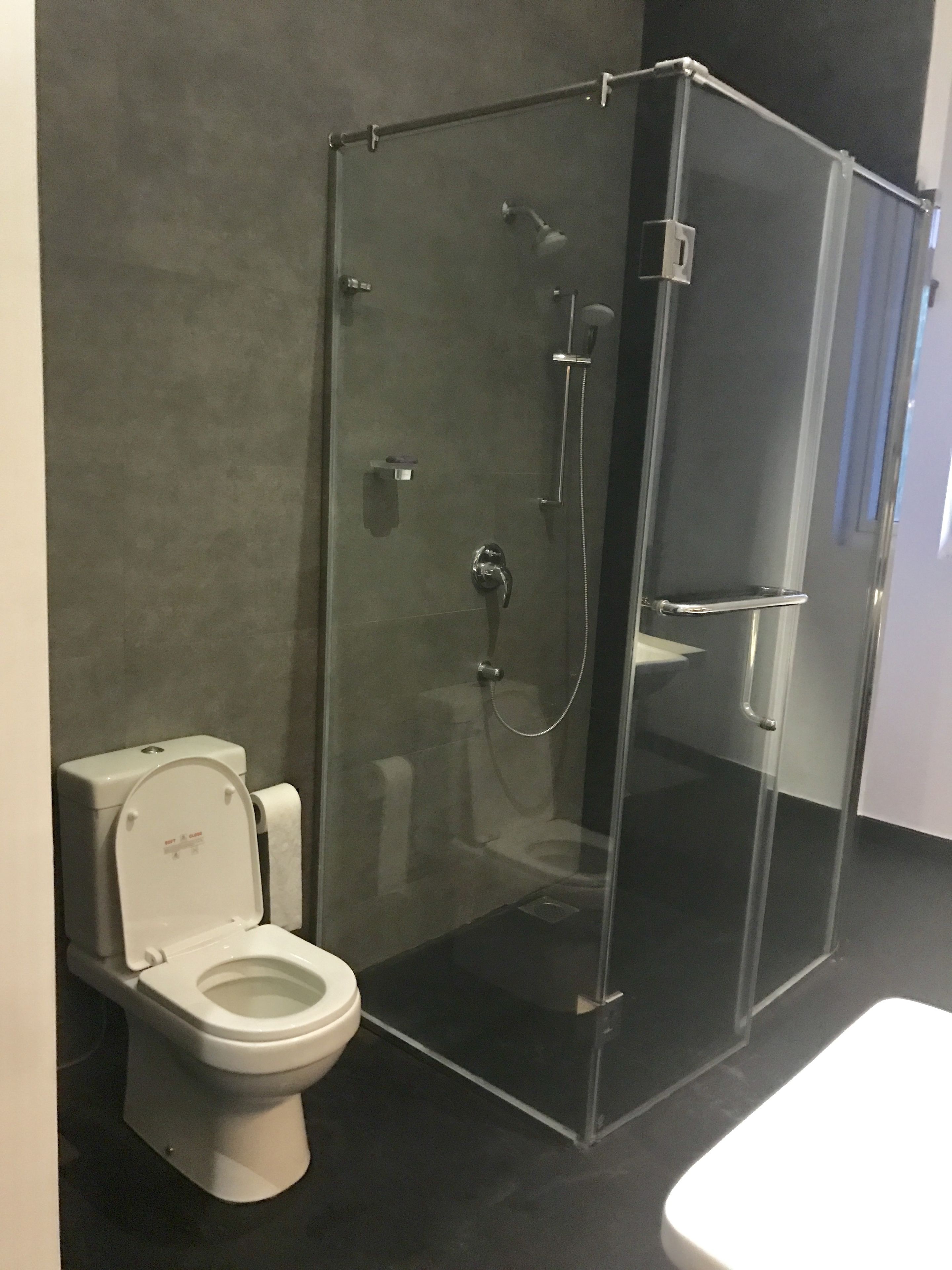 Un baño moderno con cabina de ducha de vidrio, inodoro blanco y encimera negra.