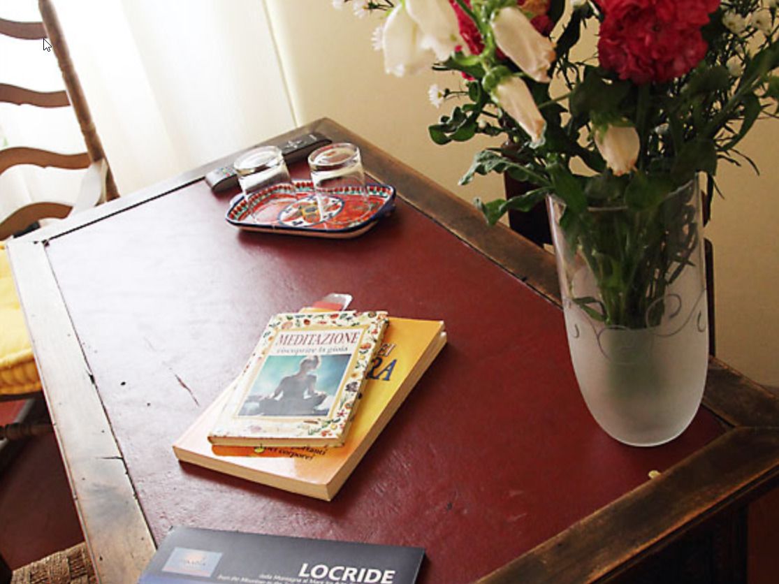 Una mesa de madera con un libro, una bandeja y un jarrón con flores.