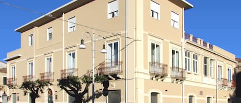 Un edificio de varios pisos con balcones, un farol y un cielo azul despejado.