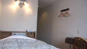 Une chambre d’hôtel comprenant un lit, une table de chevet, un téléphone et un bureau avec une chaise.