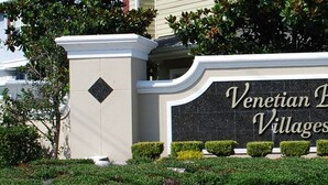 Placa para Venetian Bay Villages, com design moderno e paisagismo bem cuidado.