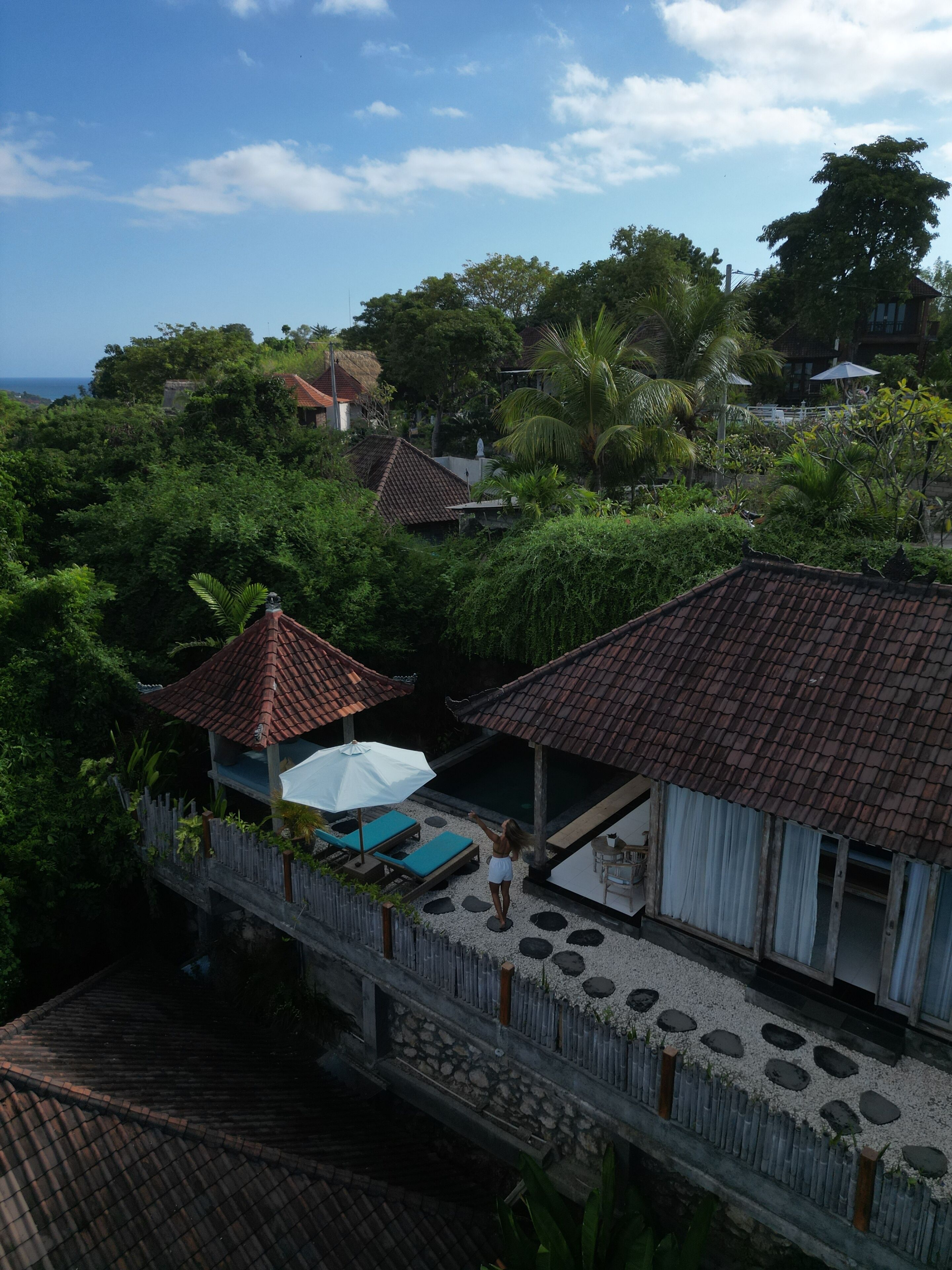 A tropical resort with a pool area, covered seating, and a view of the ocean.