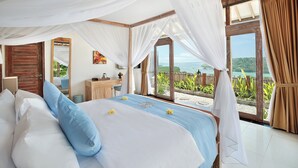 A bedroom with a bed, a wooden desk, a mirror, and a view of the sea. - The Acala Shri Sedana (Lembongan Island)