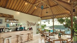 A restaurant with a wooden interior, a bar area, and a view of the sea. - The Acala Shri Sedana (Lembongan Island)