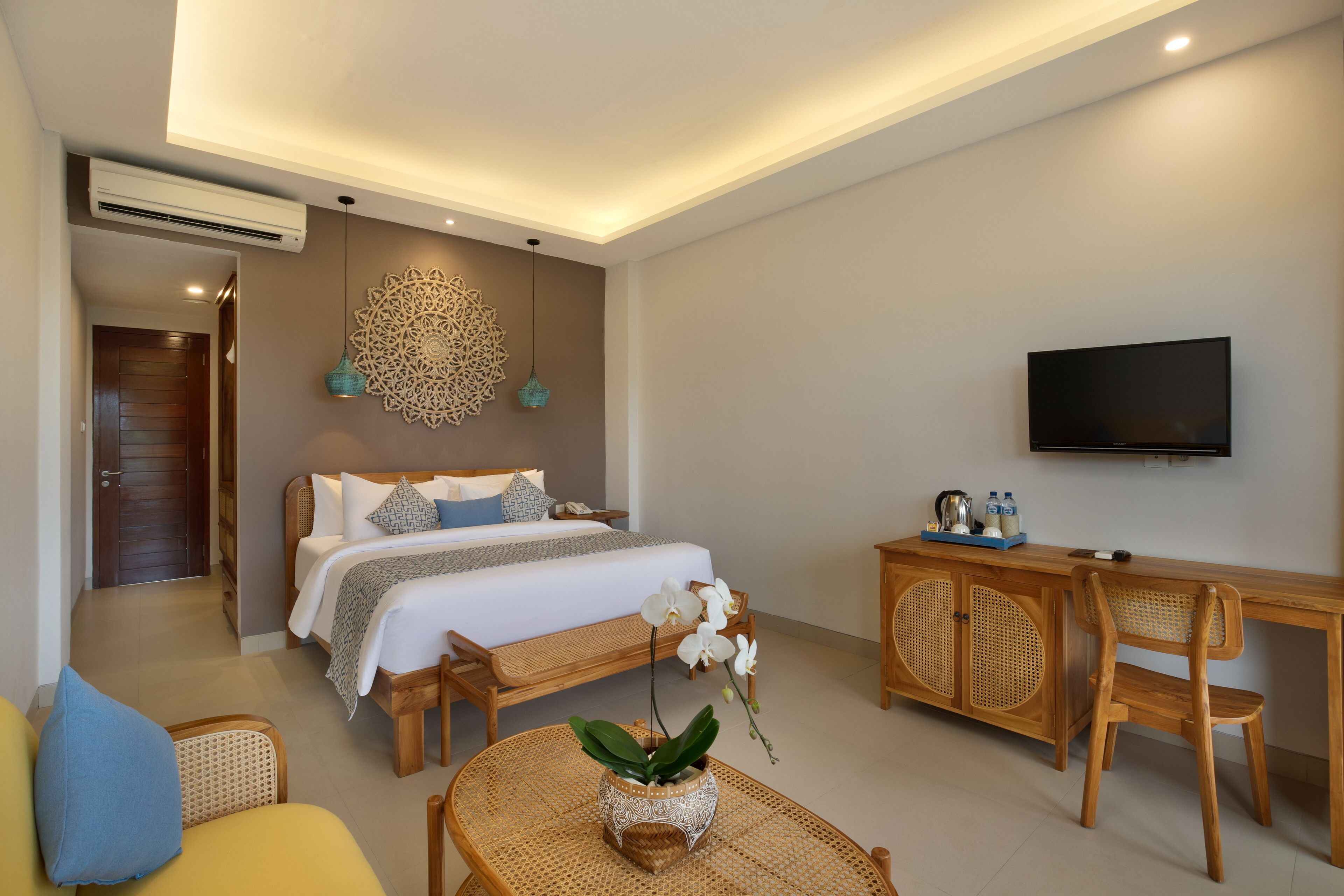 A modern hotel room with a bed, a desk, a television, and a dining area.