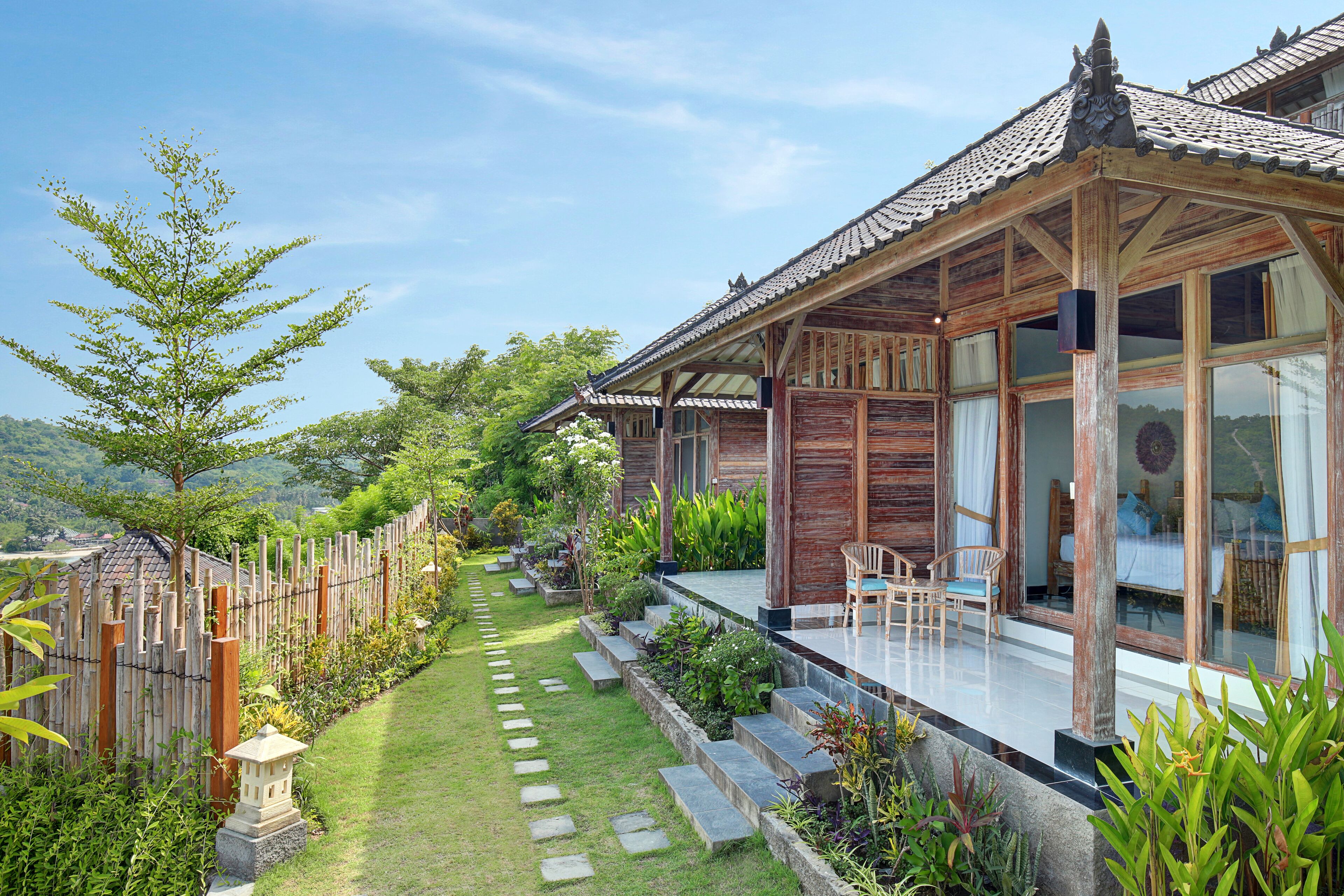 A traditional wooden house with a tiled roof, a garden with stepping stones, and a view of the landscape.