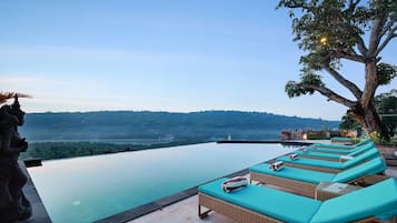 Una piscina al aire libre, sombrillas, sillones reclinables de piscina