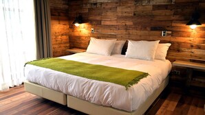 Een moderne slaapkamer met een houten wand, een bed met witte lakens en twee bedlampjes.