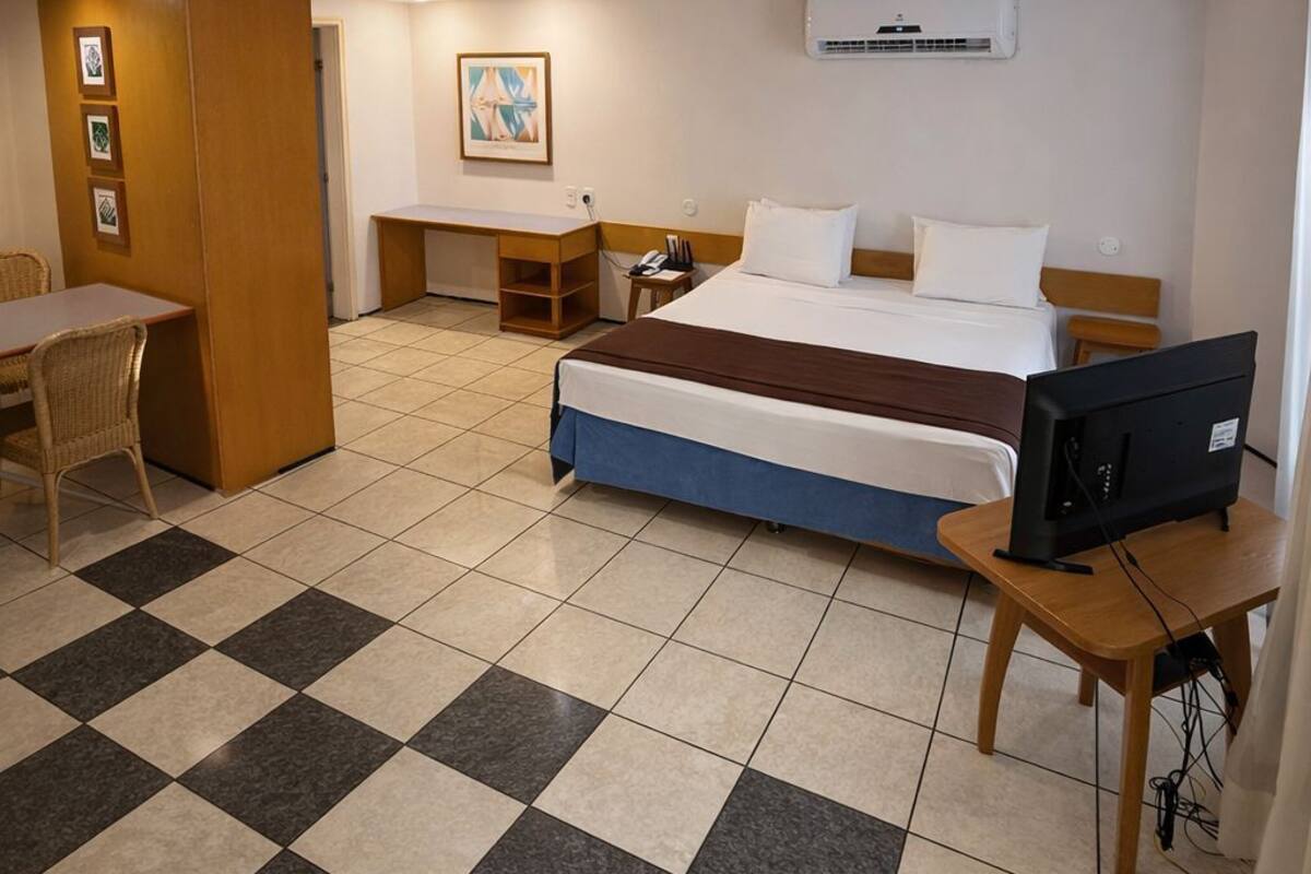 Ein Hotelzimmer mit Bett, Schreibtisch, Stuhl und Fernseher.