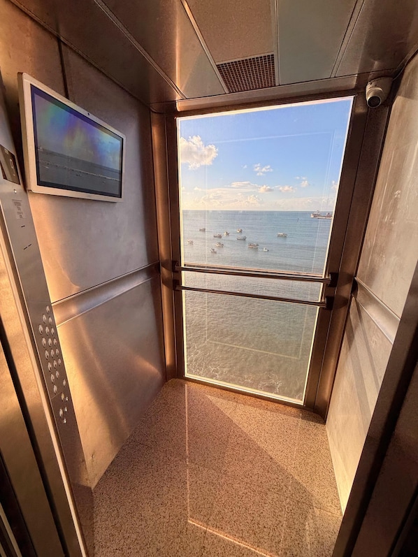 An elevator with a view of the sea and boats, a control panel, and a textured floor. - Iate Plaza Hotel (Fortaleza)