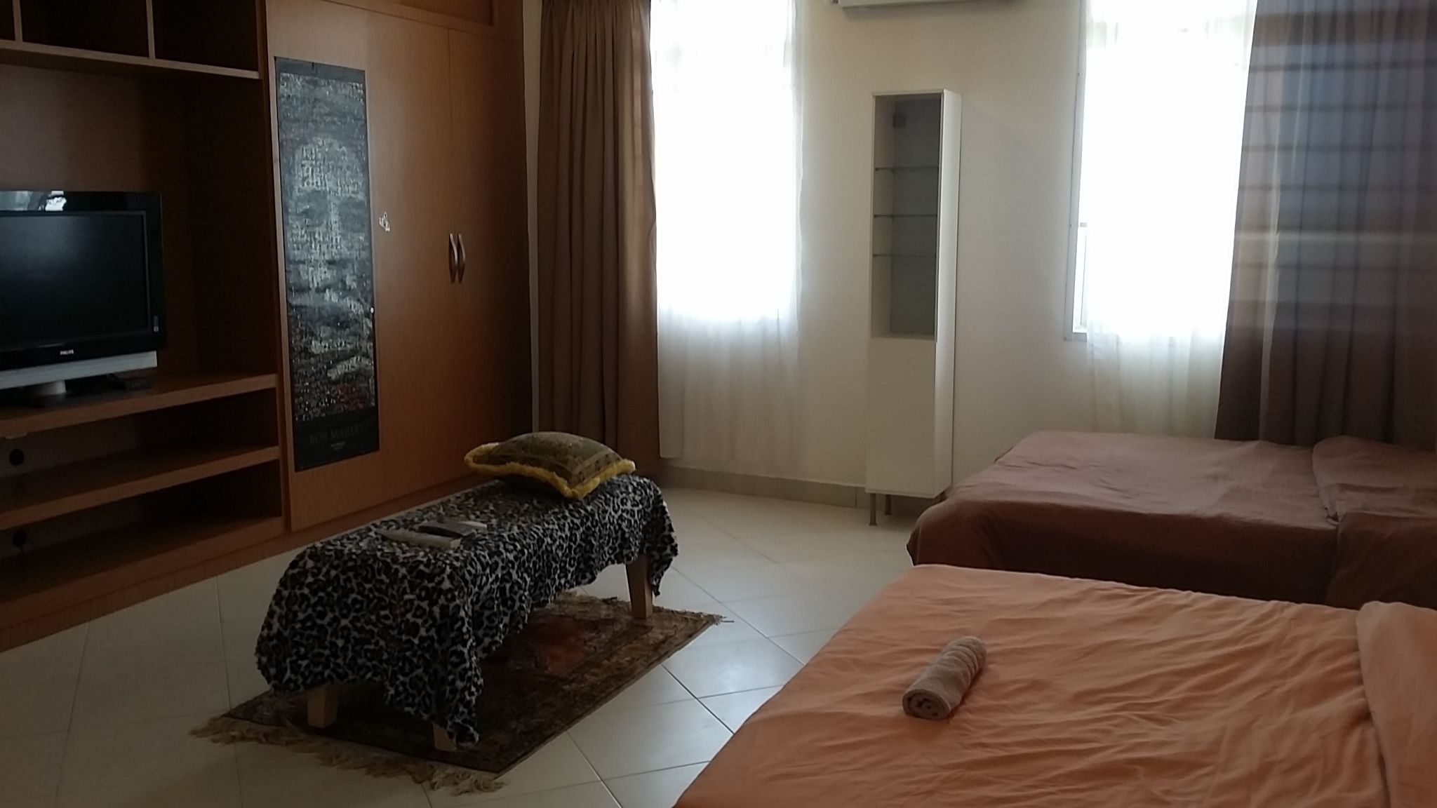 A hotel room with a bed, a bench, a television, and a wardrobe.