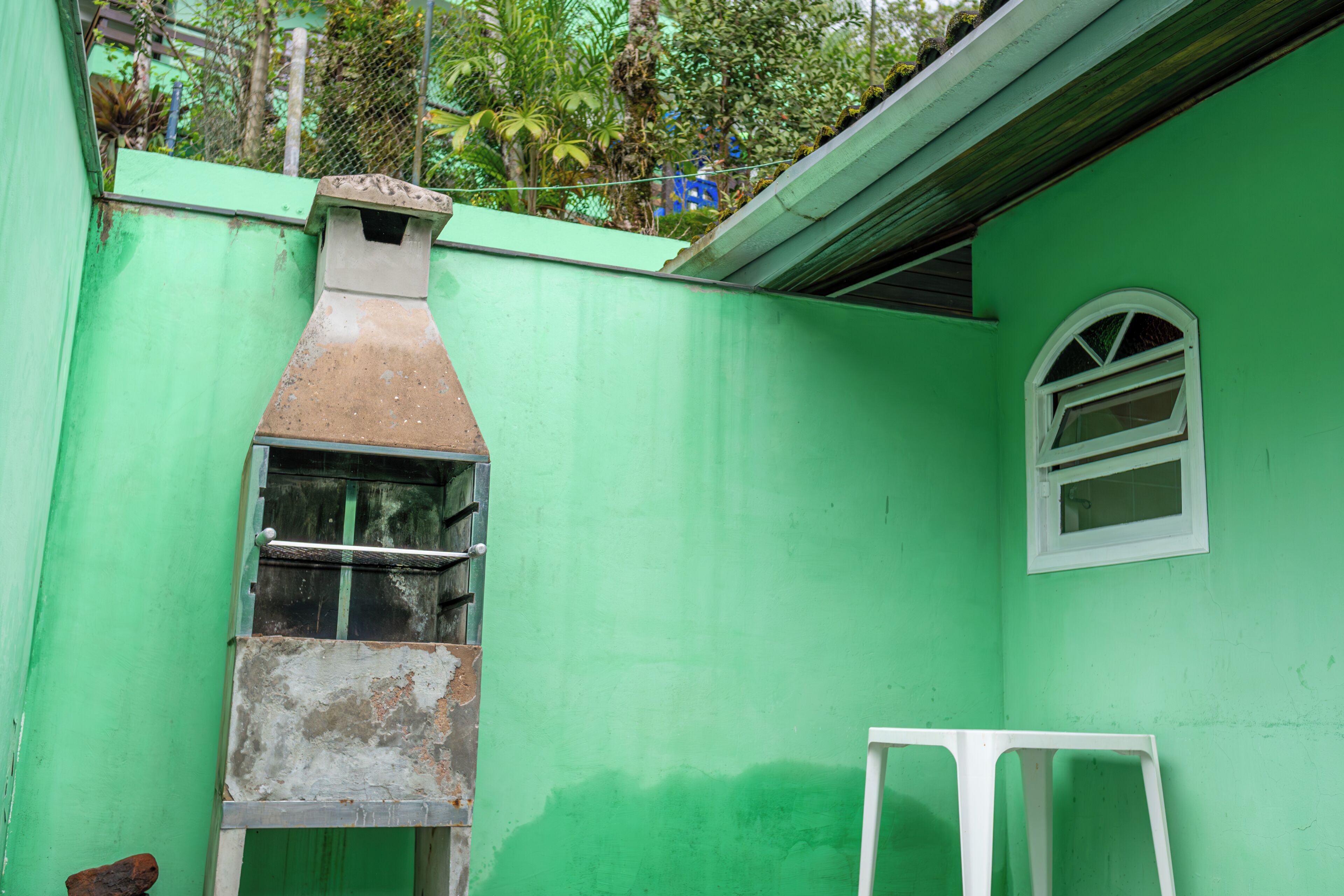 Um edifício verde com chaminé, janela e moldura de porta branca.