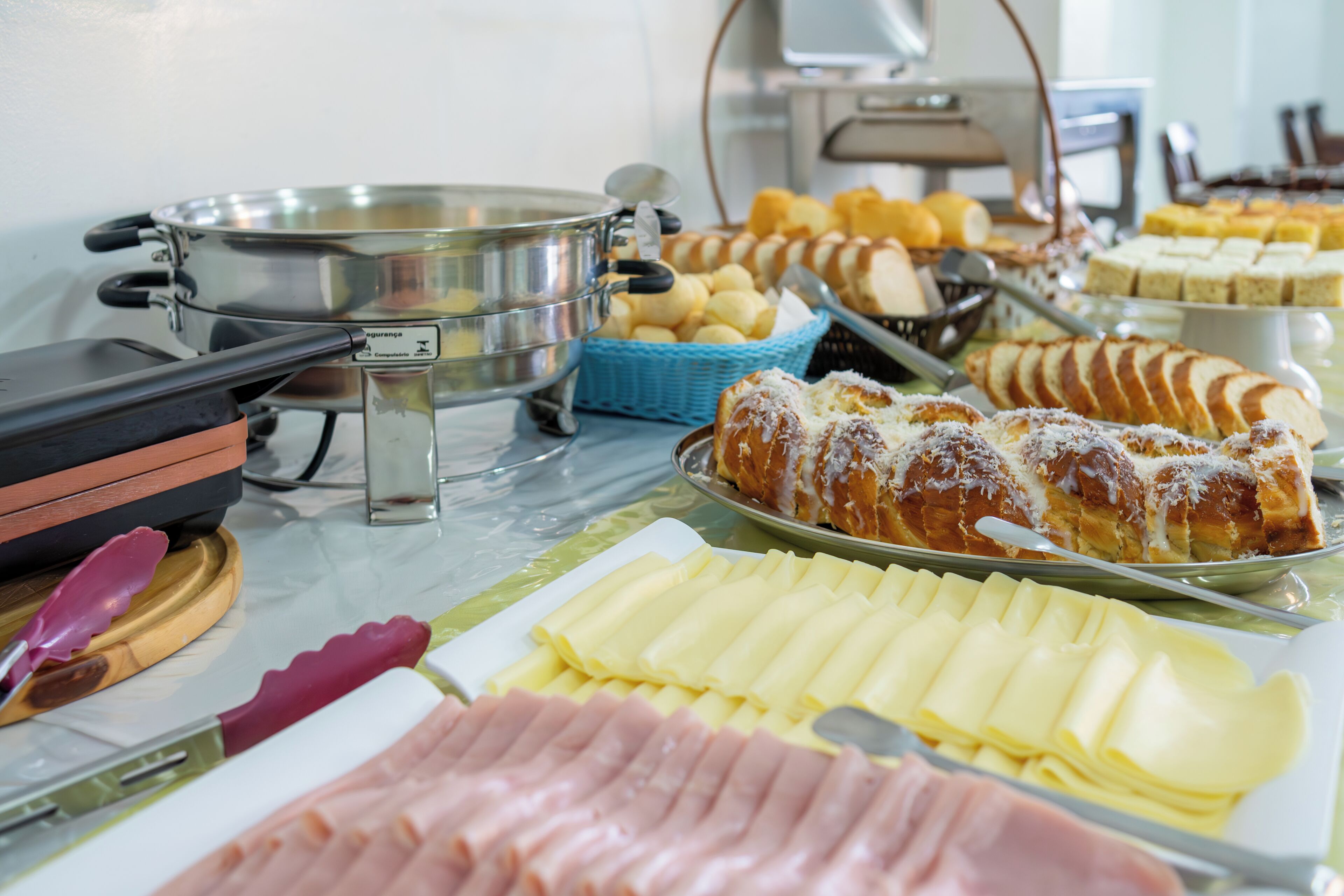 Un bufé con diversos alimentos, incluyendo pan, bollería y embutidos.