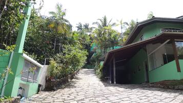A cobblestone pathway leading to a green building with a covered porch.
