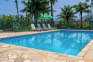 Una piscina al aire libre, sombrillas, sillones reclinables de piscina