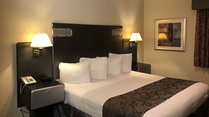 A hotel room with a large bed, two bedside tables with lamps, a telephone, and a framed picture on the wall. - Casa Royal Inn (San Jose)