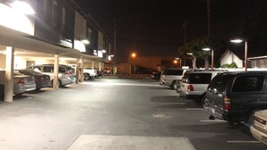 A parking lot with several cars parked under a covered area at night. - Casa Royal Inn (San Jose)