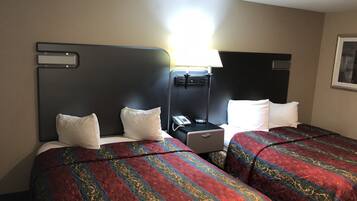 Quarto de hotel com duas camas, cada uma com colcha estampada, mesa de cabeceira com telefone e luminária.