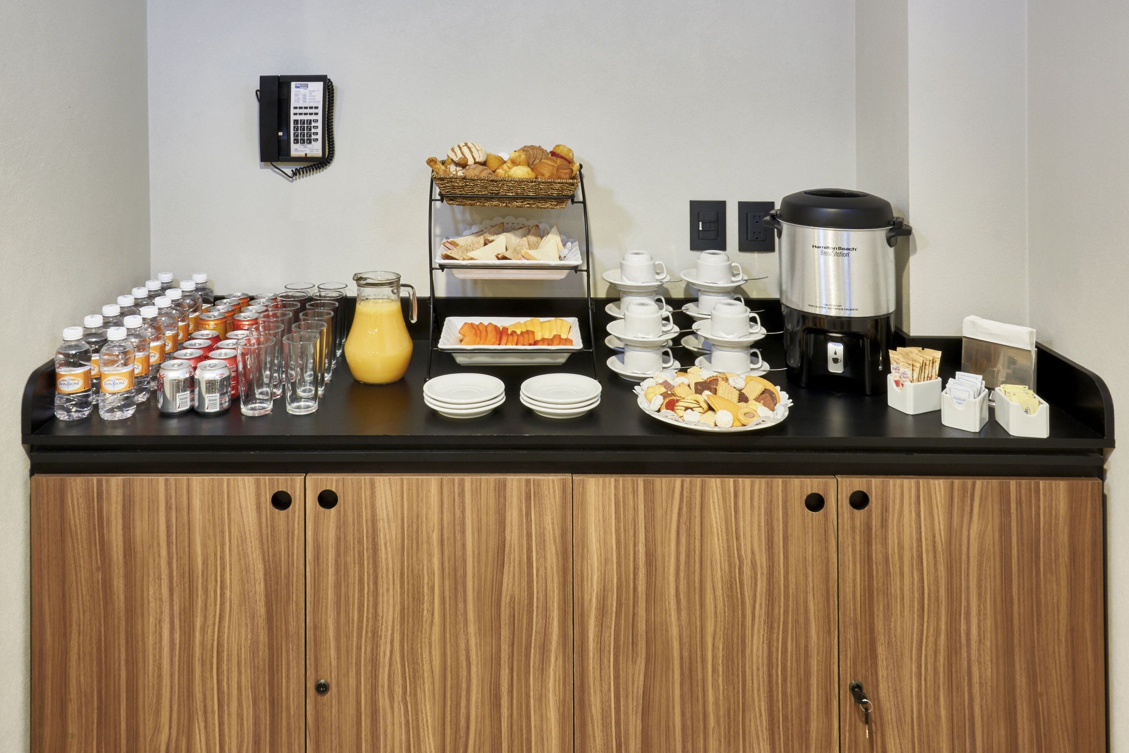 Um buffet de café da manhã com diversos alimentos, bebidas e uma cafeteira.