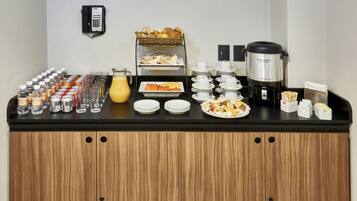 Um buffet de café da manhã com diversos alimentos, bebidas e uma cafeteira.