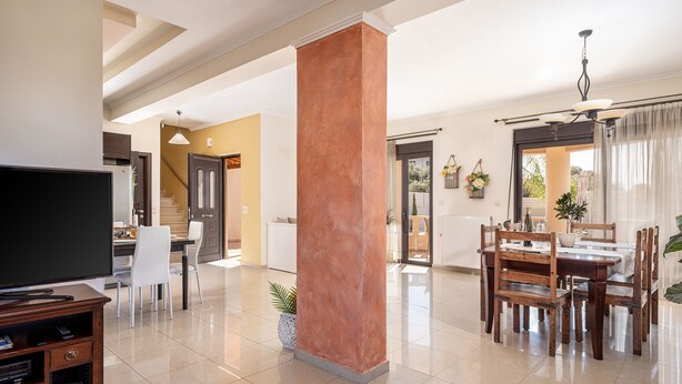 A spacious living area with a television, dining table, and chairs. - Villa Fanouris (Chania)