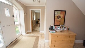 A hallway with a wooden dresser, a rug, and a painting on the wall. - The Stables 10037 (Lismullin)